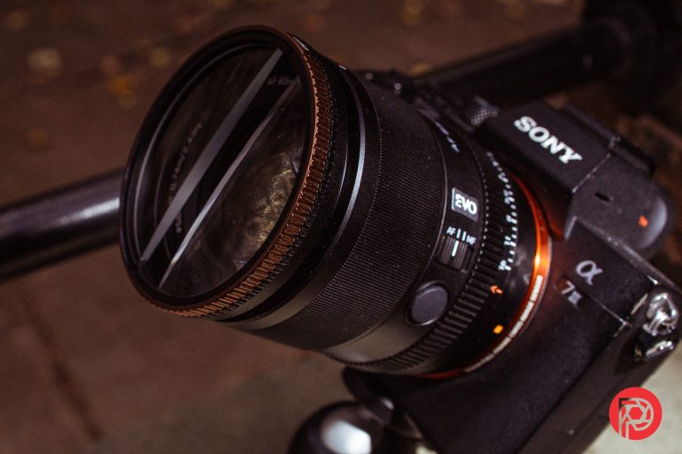 Close-up of a Sony Alpha camera with a lens mounted, set up on a tripod outdoors.