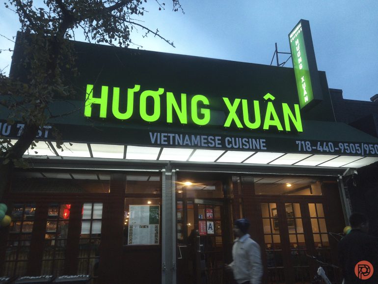 A Vietnamese restaurant with a bright green sign reading Hương Xuân at dusk.