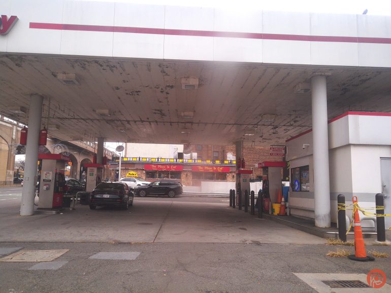 Two cars parked at a gas station under a canopy with a convenience store on the right.