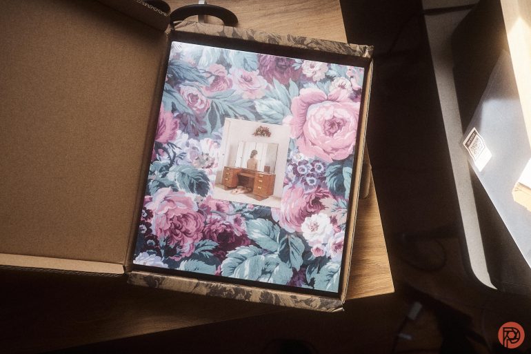 A floral-patterned vinyl record in a box, featuring a small photo of a person at a wooden piano.