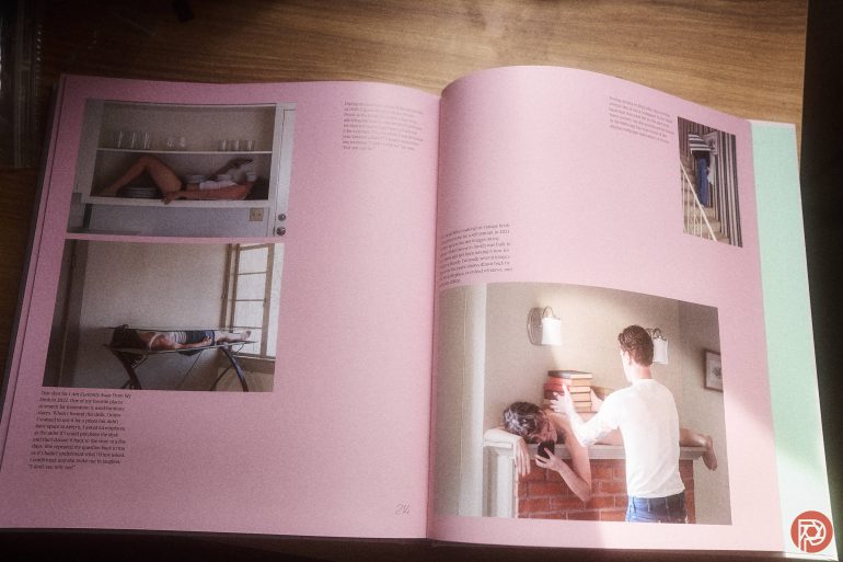 Open book with photos of people posing creatively in rooms, displayed on a wooden surface.