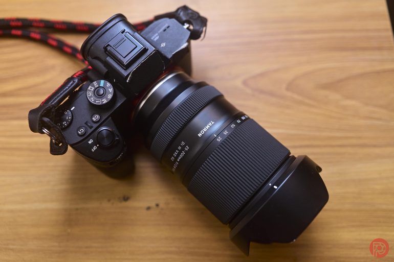 A black digital camera with a large zoom lens sits on a wooden surface.