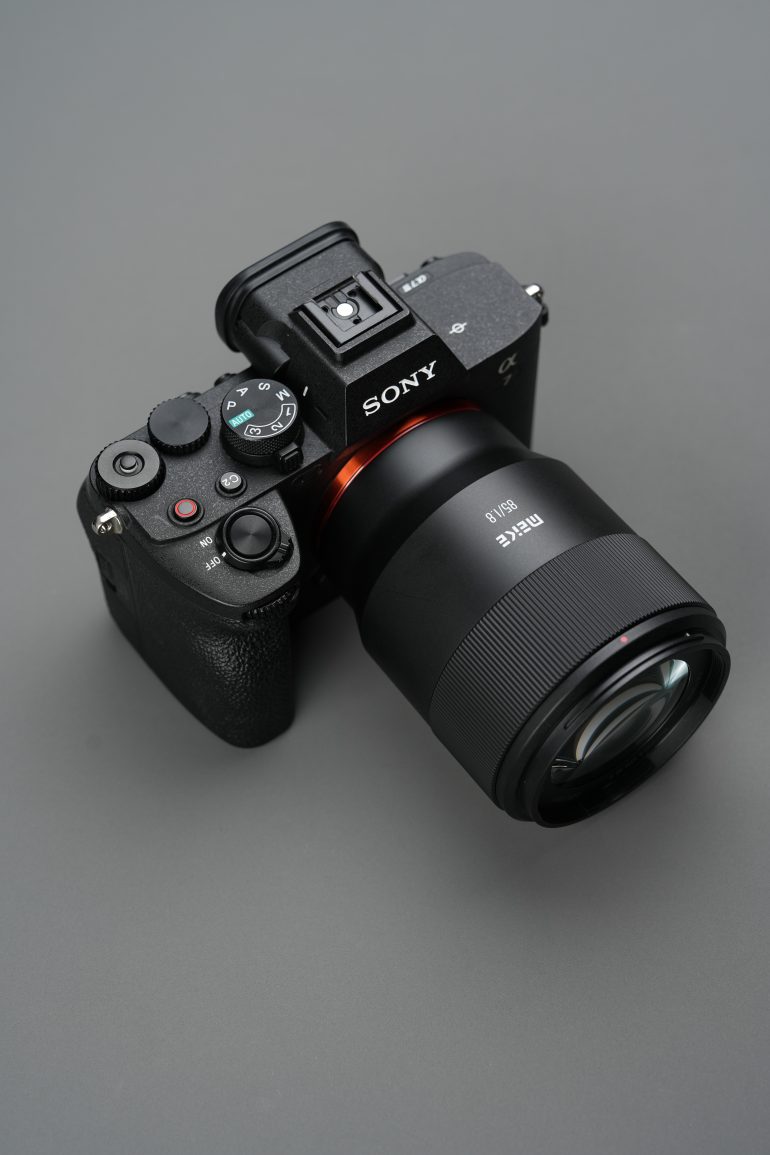 A Sony digital camera with a large lens is placed on a gray surface.