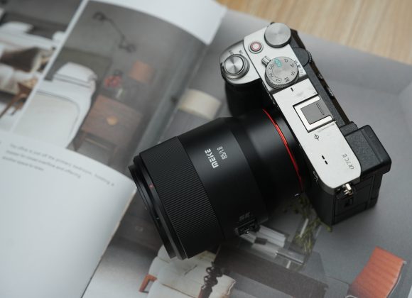 A digital camera with a Meike lens rests on an open magazine featuring interior designs.