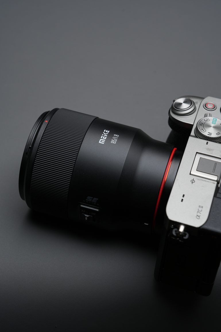 A close-up of a digital camera with a large lens against a dark gray background.