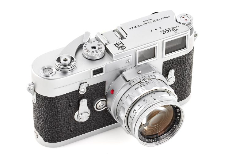 A silver and black vintage Leica film camera with a lens, viewed from a high angle.