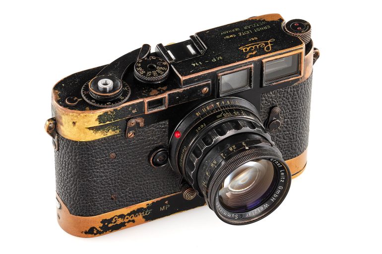 A vintage black and gold Leica MP film camera with visible wear and a Summilux lens attached.