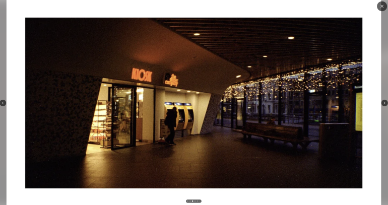 Dimly lit mall entrance with ATMs, a store, and string lights reflecting on glass windows.