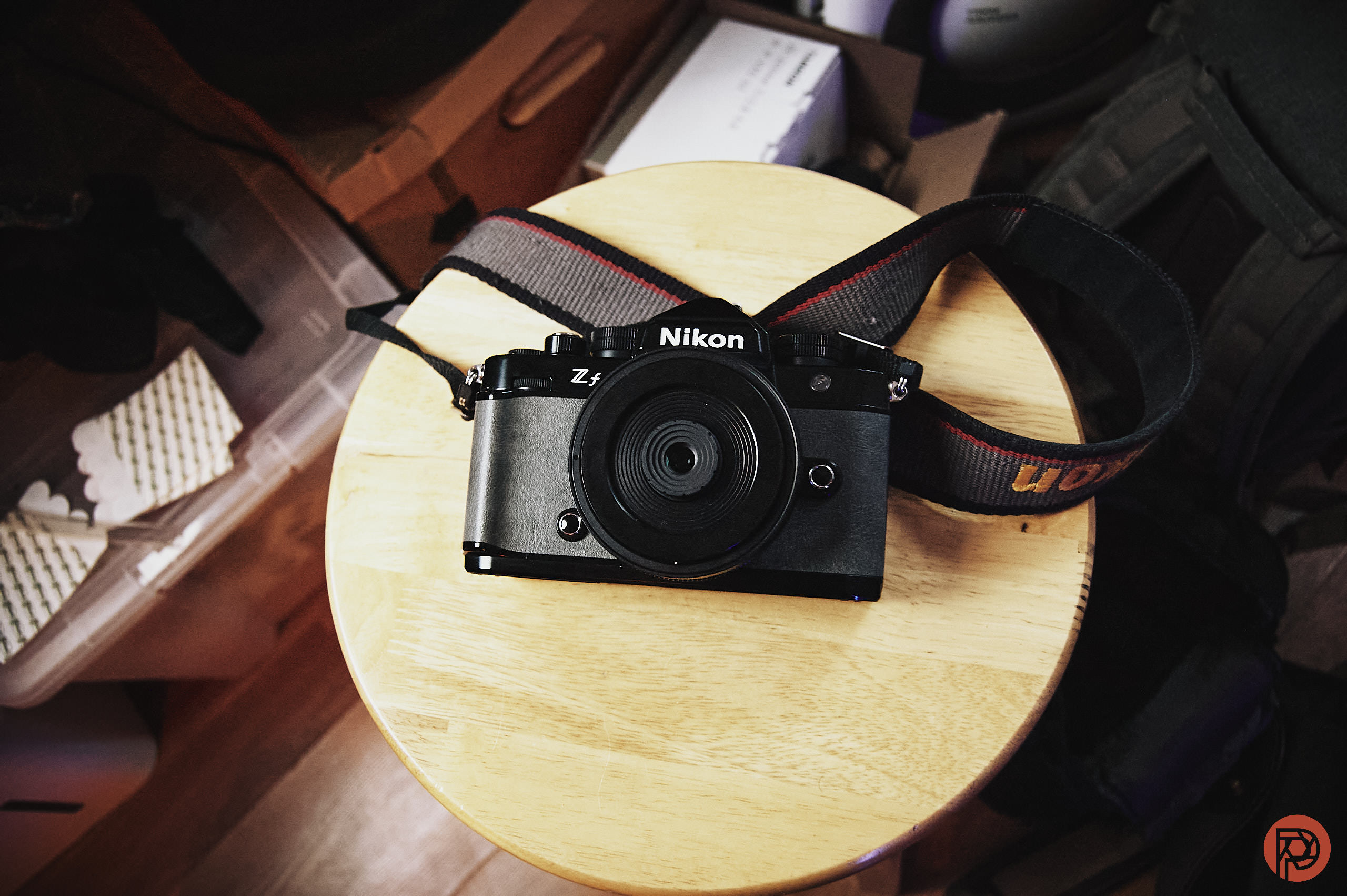Nikon Z fc camera with a strap resting on a round wooden stool, viewed from above.