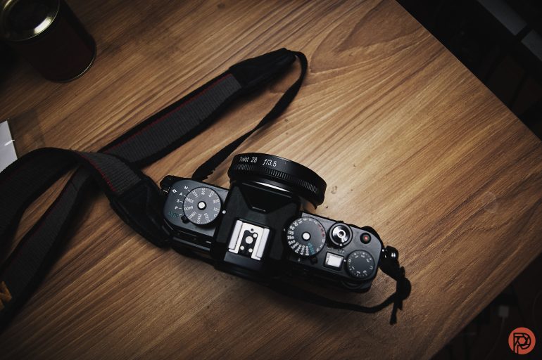 Top view of a black camera with a strap resting on a wooden table.