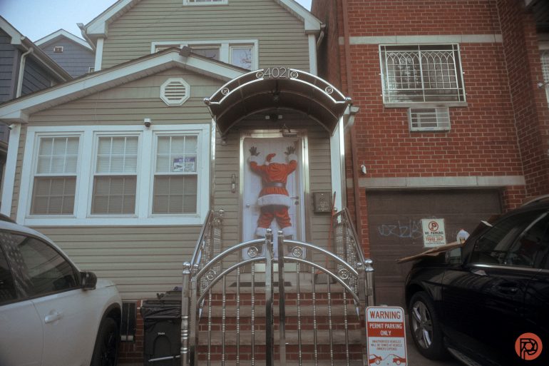 Front view of a house with a basketball player mural on the door and cars parked on both sides.