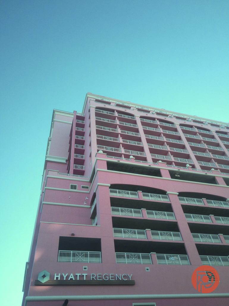 Pink Hyatt Regency hotel building against a clear blue sky, viewed from a low angle.