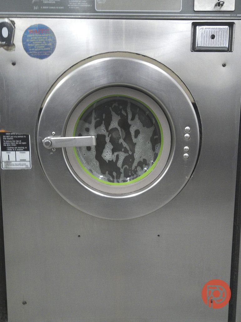 Front view of a washing machine with soap suds visible through the circular glass door.