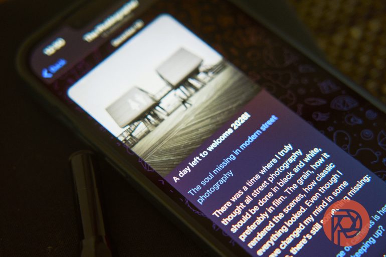 A smartphone screen displays an article with a black-and-white pier photo and highlighted blue text.