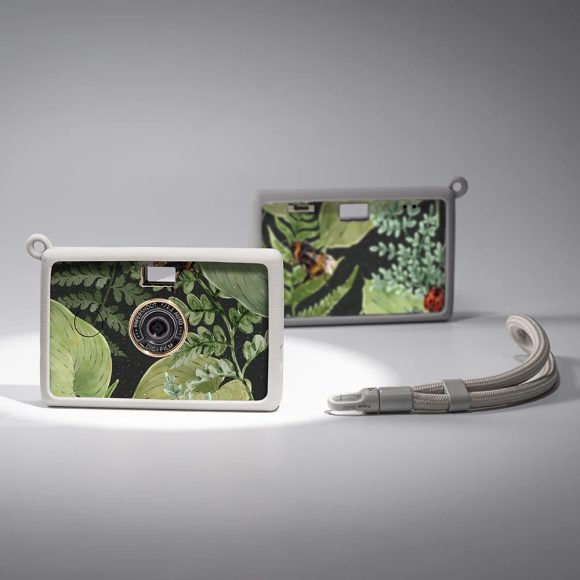 Two compact cameras with leafy green and nature-themed designs and white frames, on a grey background.