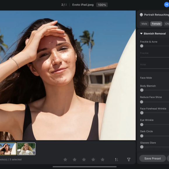Woman with long brown hair holds a surfboard, smiling under the sun with palm trees in the background.