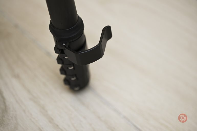 Close-up of a tripod leg lock on a light wooden floor.