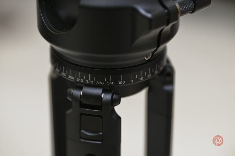 Close-up of a black tripod head with a circular degree scale and adjustment knob.