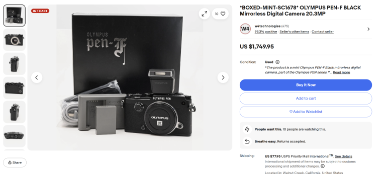 Olympus PEN-F camera, box, battery, charger, and strap displayed on a white surface.