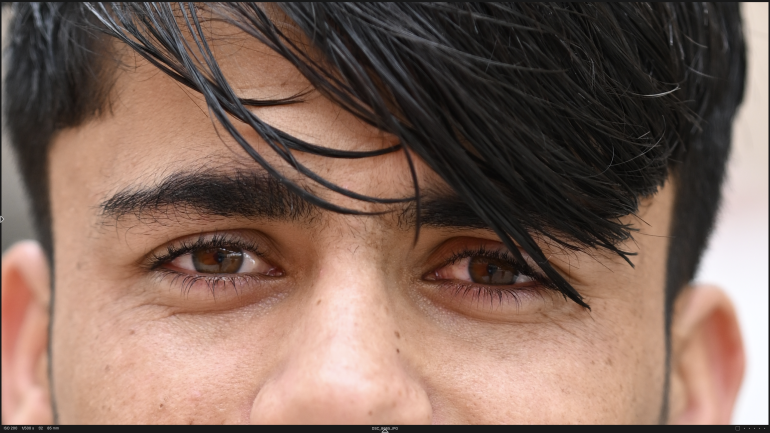 Close-up of a persons face, focusing on brown eyes and dark hair falling over the forehead.
