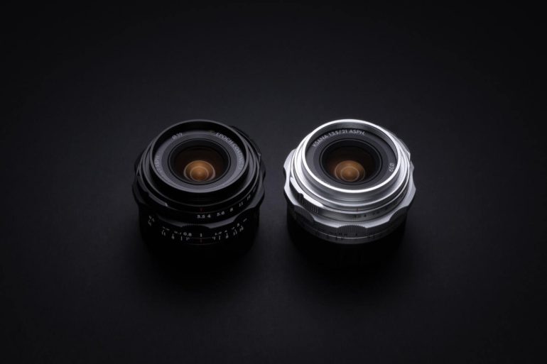 Two camera lenses, one black and one silver, placed side by side on a dark background.