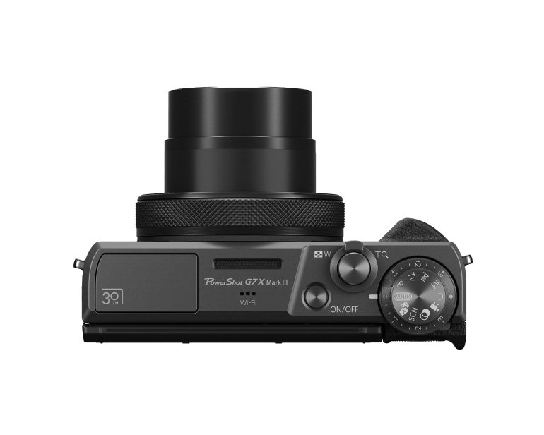 Top view of a black Canon PowerShot G7X Mark III camera with its lens extended and control dials visible.