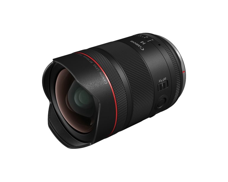 Canon camera lens with a red ring, wide glass element, and lens hood, viewed at an angle on a white background.
