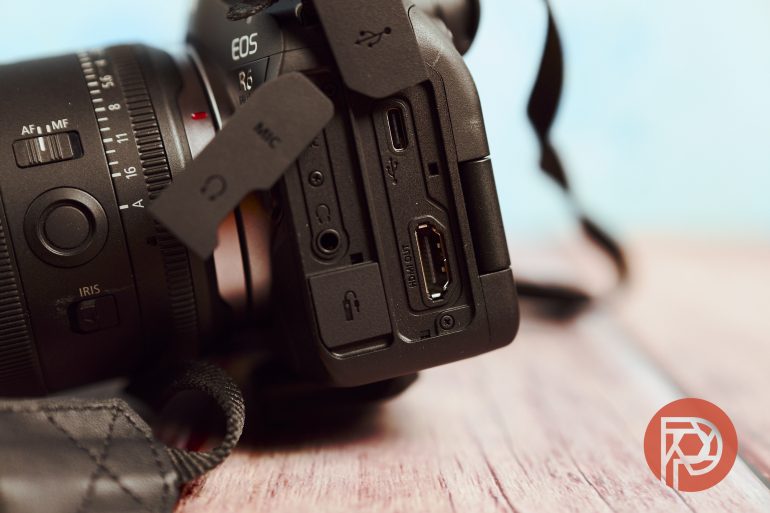 Close-up of a camera’s side ports, including HDMI, microphone, and USB, on a wooden surface.