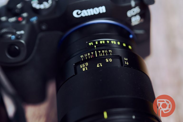 Close-up of a Canon camera with a focus on the yellow markings of a Zeiss lens.