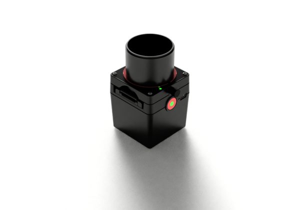 A small black electronic device with a circular lens and a red button on a white background.
