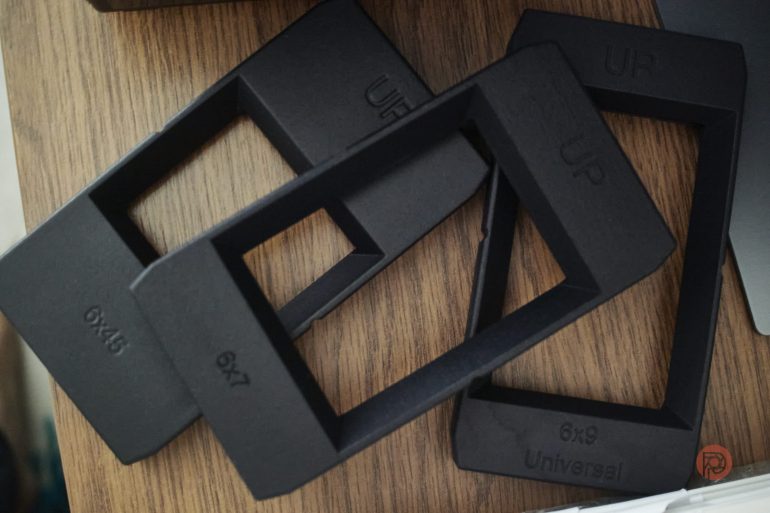 Three black plastic rectangular film holders labeled 6x4.5, 6x7, and 6x9 lie on a wooden surface.