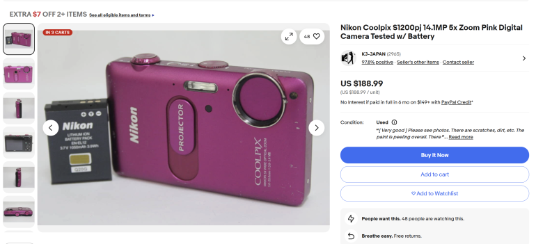 Pink Nikon Coolpix S1200pj camera and battery displayed on a white background in an online listing.