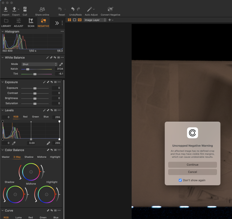 Photo editing software shows an Uncropped Negative Warning pop-up next to film scan adjustment tools.