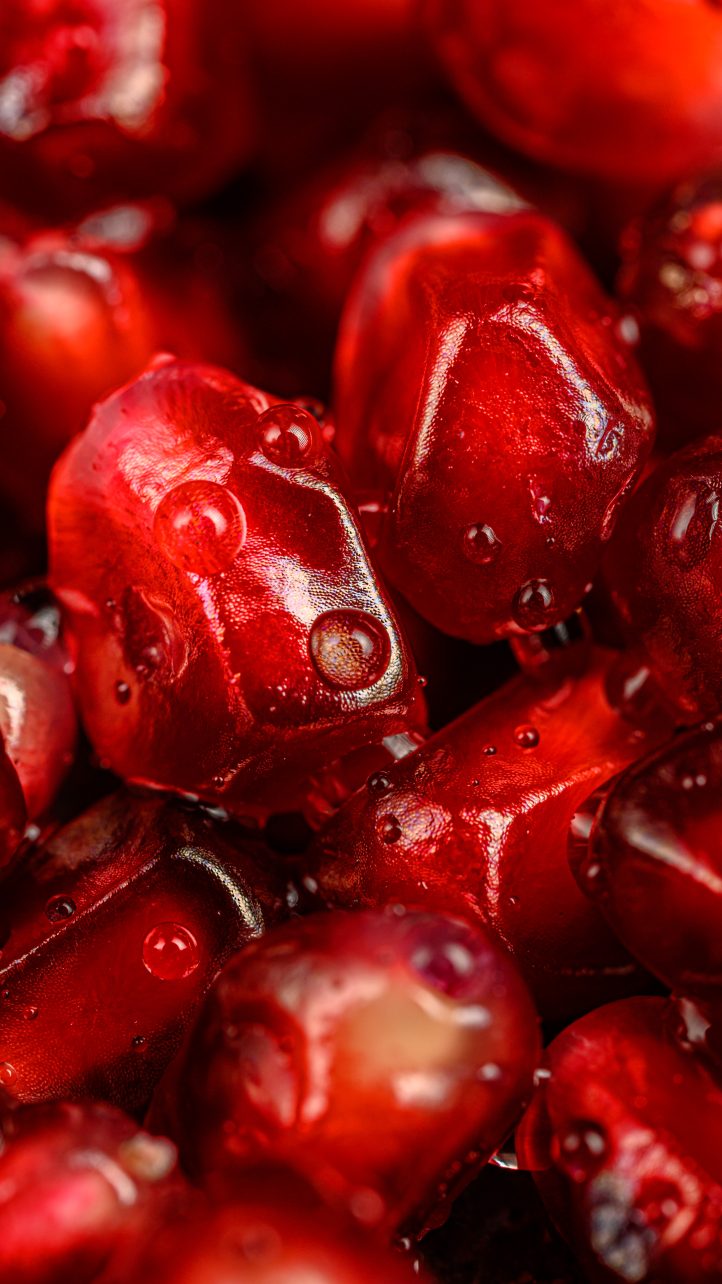 Close-up of fresh, juicy pomegranate seeds with glistening drops of water on their red surfaces.