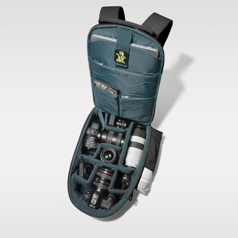 Teal camera backpack open, showing organized DSLR cameras and lenses inside padded compartments.