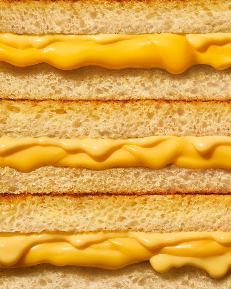 Close-up of stacked grilled cheese sandwiches showing layers of toasted bread and melted cheese.