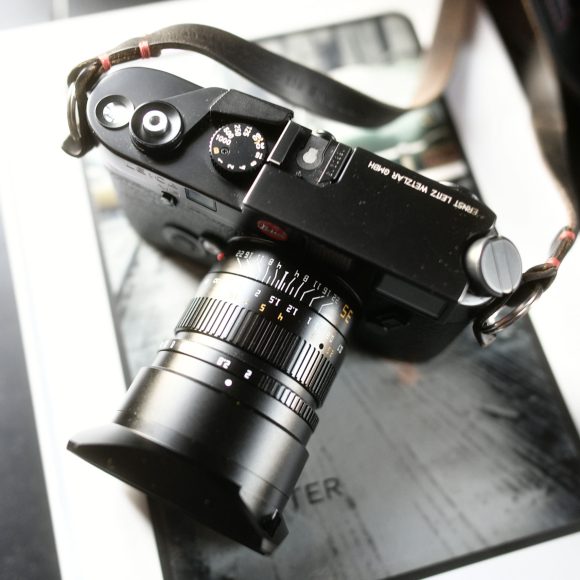 A black Leica camera with a lens, resting on top of a closed book.