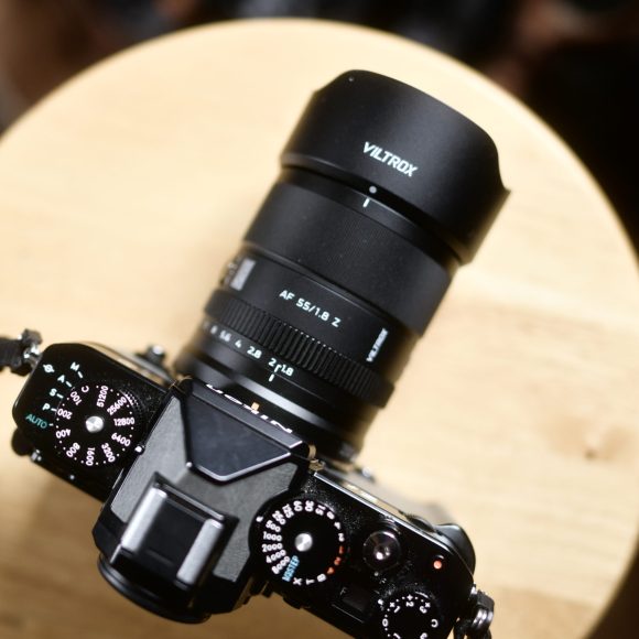 A black Viltrox camera with dials, resting on a round wooden surface, viewed from above.