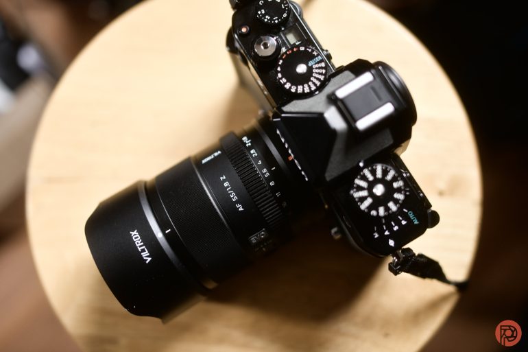 A black Viltrox camera rests on a wooden surface, viewed from above, showing its dials and lens.
