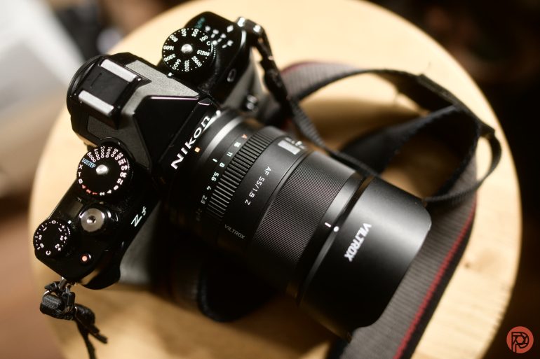 A Nikon Z5 camera with a Viltrox lens and strap, placed on a round wooden surface.