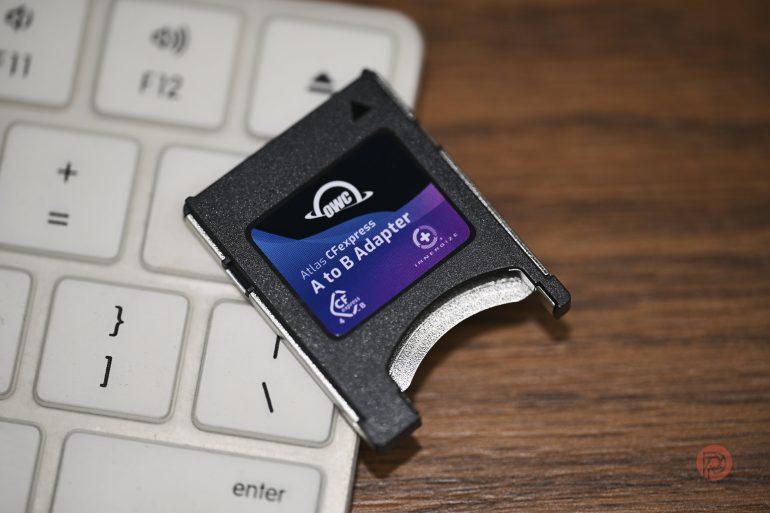A memory card adapter rests on a white keyboard next to a wooden surface.