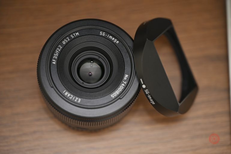A camera lens and its lens hood are placed on a wooden surface.