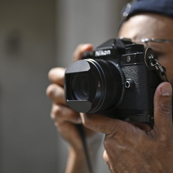 A person holding a Nikon camera up to their face, preparing to take a photo.