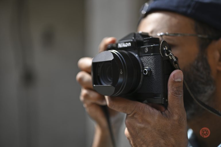 A person holding a Nikon camera up to their face, preparing to take a photo.