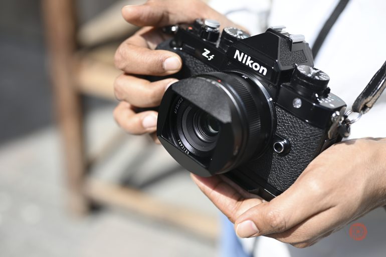 Person holding a Nikon Z f camera outdoors in bright sunlight.