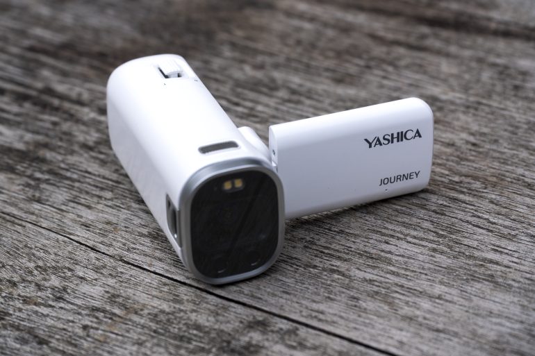 A white Yashica Journey camcorder sits on a weathered wooden surface with its screen flipped out.