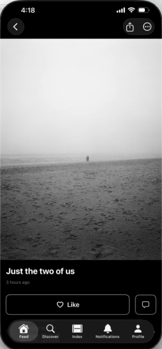 Two people walk together on a foggy, empty beach, with footprints visible in the sand.