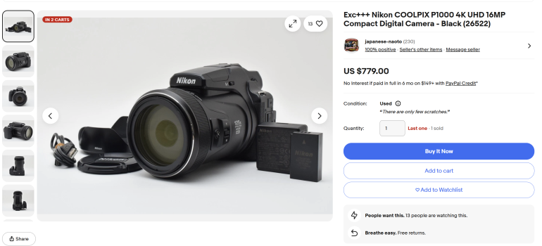 Nikon COOLPIX P1000 camera with lens, battery, and lens cap displayed on a white surface.