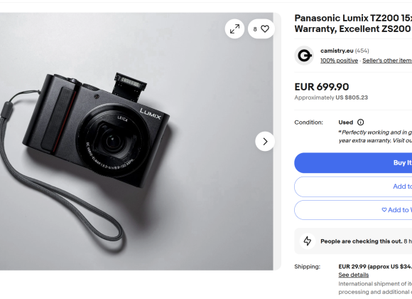Black Panasonic Lumix digital camera with strap on a white surface, displayed on an online sales listing page.