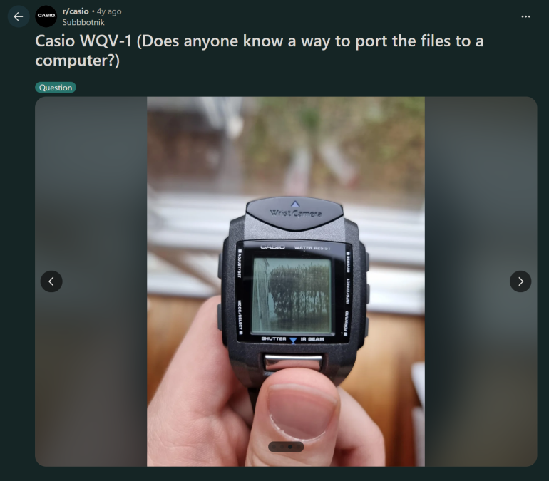 A hand holds a Casio WQV-1 wrist camera watch displaying a blurry image on its screen.